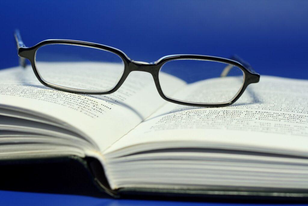 Lesebrille auf aufgeschlagenem Buch